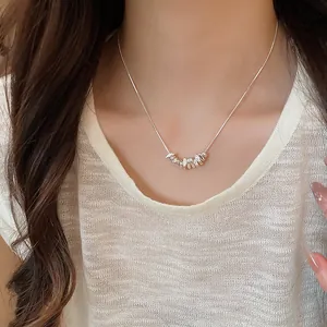 Macro view of minimalist silver necklace with irregular bead pendants on model's neck