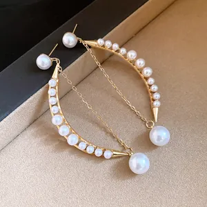 Gros plan détaillé des élégantes boucles d'oreilles croissant en or avec perles et glands