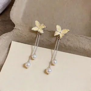 Detailed close-up view of elegant yellow enamel butterfly tassel earrings with white pearls