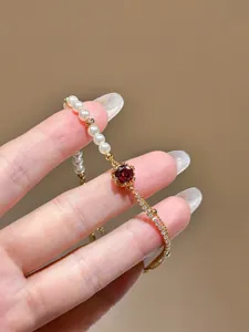 Detail shot of an adjustable 18K gold plated bracelet with pearls and red zircon