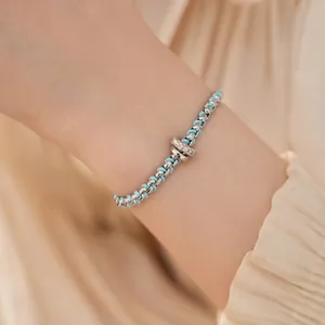 Handgefertigtes blaues geflochtenes Armband mit Zirkonia-Anhänger am Handgelenk getragen.