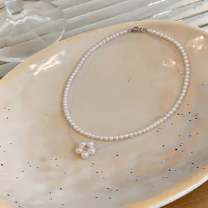 Primo piano di una collana a due fili di perle con ciondolo a forma di fiore di perla.