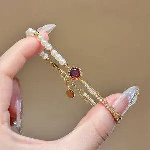 Close-up detail of 18K gold plated pearl bracelet with central red zircon and pave stones