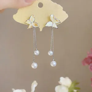 Close-up of butterfly stud earrings with silver-tone tassels and lustrous white pearls