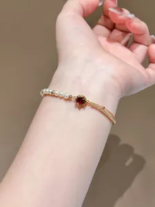 Close-up of elegant 18K gold plated bracelet with red zircon and pearls on wrist