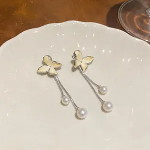 Detailed macro view of elegant yellow enamel butterfly drop earrings with pearl tassels