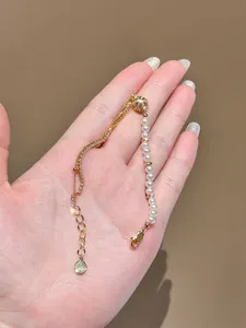 Detail of a 18K gold-plated bracelet with elegant pearls and zirconia held in hand