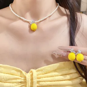 Detailed close-up view of a pearl necklace and earrings set featuring yellow lemon pendants