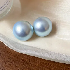 Detalle macro de pendientes de perlas azul claro iridiscentes sobre fondo de tela de seda