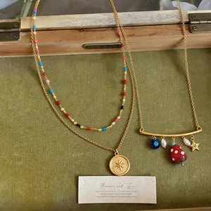 Close-up of gold-tone necklaces featuring strawberry, pearl, and star charm pendants.
