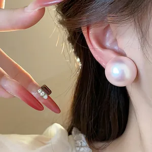 Primer plano detallado de los elegantes pendientes de perlas rosas iridiscentes en la oreja