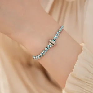 Nahaufnahme eines blau geflochtenen Armbands mit silbernen Gliedern und Zirkonia