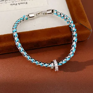Nahaufnahme eines blauen Flechtarmbands mit einem funkelnden Zirkonia-Ring-Charm-Anhänger