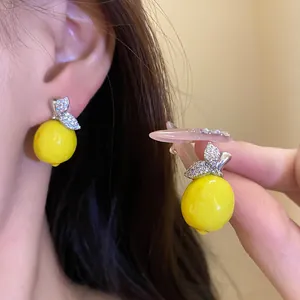 Detailed close-up of vibrant yellow lemon drop earrings decorated with sparkling zircons