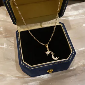 Close-up of 18k gold plated necklace with zircon moon and star pendants in box