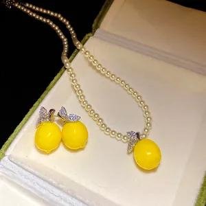 Detailed view of zircon lemon pendant and earrings with elegant pearl bead chain