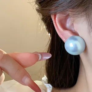 Primer plano de un elegante pendiente de perla iridiscente en la oreja de una modelo, lujo