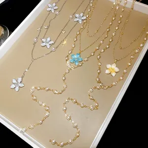 Elegant multi-layer necklace with enamel flower pendants and pearls on a display tray