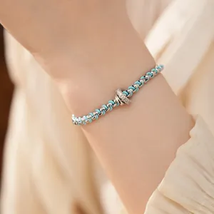 Nahaufnahme eines blauen Kordel- und Silberkettenarmbands mit einem Zirkonia-Ring