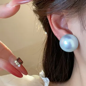 Primer plano de pendientes de perlas iridiscentes estilo francés con agujas de plata.
