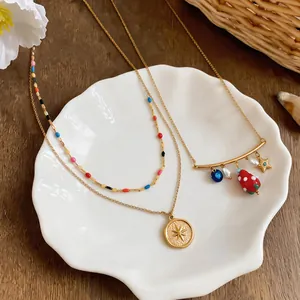Close-up of sweet gold necklaces featuring strawberry and starburst charms on a plate