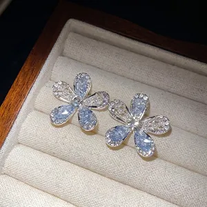 Boucles d'oreilles fleurs argentées avec pétales en verre bleu et détails cristal.