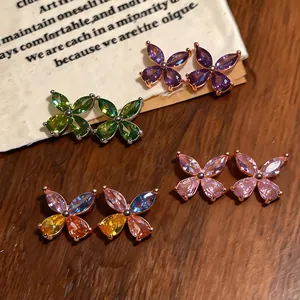 Detailed view of colorful zircon butterfly stud earrings on a rustic wooden background