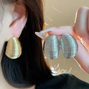 Detailed view showing the ribbed texture of elegant oval stud earrings in gold and silver
