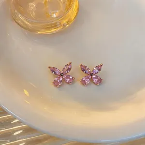 Detail view of pink flower stud earrings with zircons and an elegant gold setting.
