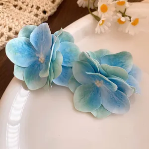 Dettaglio delle mollette per capelli a fiore in tessuto azzurro con petali fini