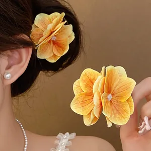 Primo piano del fermaglio per capelli a fiore in tessuto arancione con petali a strati