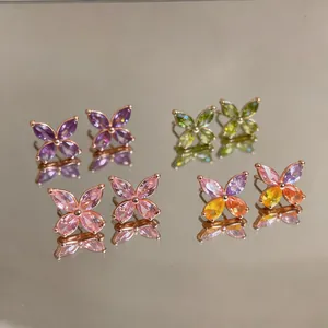 Detailed view of colorful zircon flower stud earrings in purple, green, and pink.