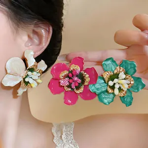 Close-up of elegant colorful enamel flower earrings with gold metallic edges