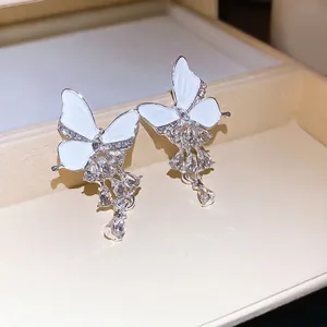 Elegante Schmetterlingsohrringe mit weißer Emaille und funkelnden Strass-Quasten.