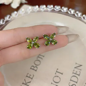 Macro view of olive green zircon flower stud earrings with a four-petal floral design