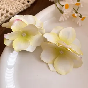 Dettaglio di eleganti fermagli per capelli a fiori in tessuto con centri di perle e petali gialli.