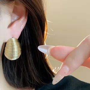 Close-up of ribbed gold oval earrings showing fine texture and light luxury style.