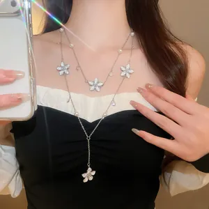Close-up of double-layer necklace with white enamel flowers and pearls on neck