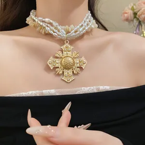 Detailed macro shot of vintage gold cross pendant on a multi-layer pearl and shell necklace