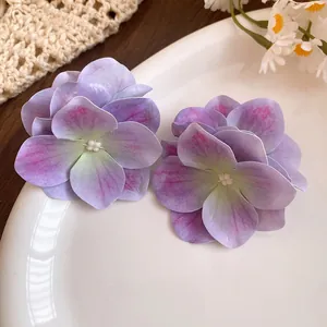 Primo piano di eleganti fermagli per capelli a forma di fiore in tessuto viola.