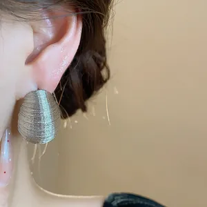 Close-up detail of silver textured oval stud earring on ear for a minimalist look