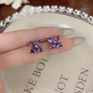 Detailed macro view of purple teardrop zirconia flower stud earrings in silver finish