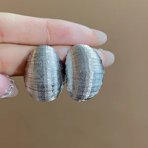 Detailed close-up of silver textured oval stud earrings with elegant ribbed finish.