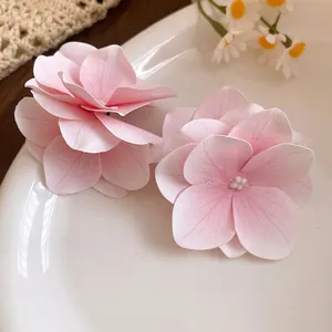 Dettaglio ravvicinato di fermagli per capelli a fiore in tessuto rosa su un piatto.