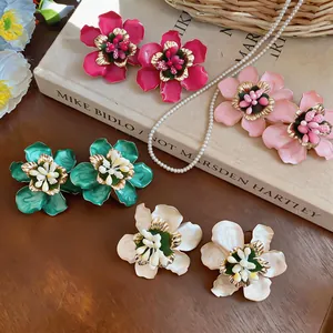 Detailed macro view of colorful metal flower stud earrings with enamel finish and pearl accents