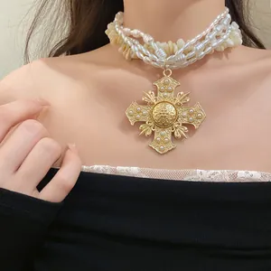 Detail view of multilayer necklace featuring pearls, shells, and a large golden cross