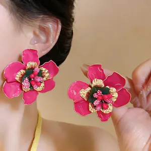 Close-up of vibrant pink enamel flower earrings with gold edges and detailed center