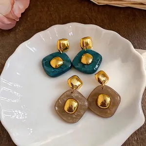 Elegant resin rhombus stud earrings with gold textured accents in teal and beige colors