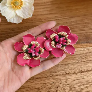 Detailed view of handmade pink enamel flower earrings with gold finish and bead center