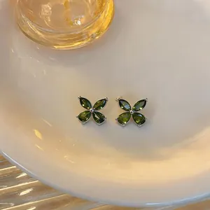 Detailed view of elegant green zircon flower stud earrings on a minimalist ceramic plate
